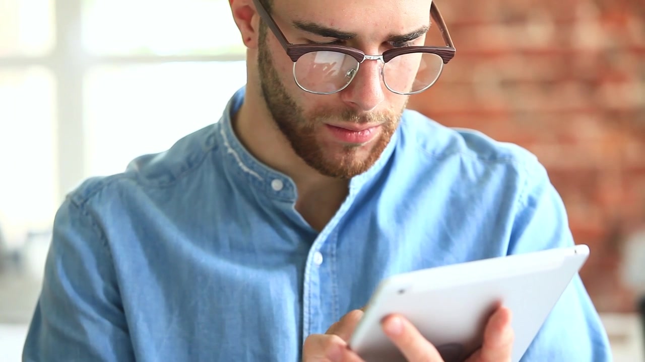 Giovane uomo che usa un tablet digitale in un ufficio moderno