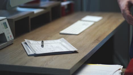 Creative-business-person's-hands-place-down-a-black-mirrorless-hybrid-photo-video-camera-on-a-modern-wood-desk-at-home-office-next-to-a-wireless-computer-keyboard,-mouse,-printer-and-computer-monitor