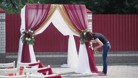 una joven decora con las flores un arco