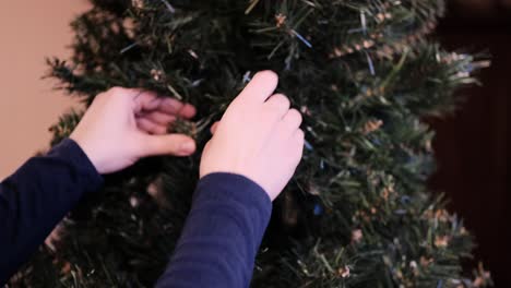 woman straightening artificial christmas tree branches, close up