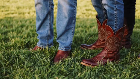 people in jeans and cowboy boots standing in green grass