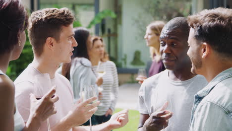 Grupo-De-Amigos-Multiculturales-Relajándose-Y-Bebiendo-Vino-Juntos-En-El-Jardín