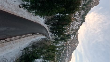 Vertical-FPV-Drone-Shot-of-Winding-Road-Through-Snowy-American-Fork-Canyon