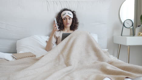 woman relaxing in bed with technology