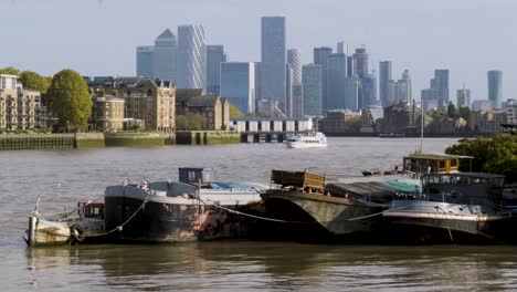 Breite-Aufnahme-Von-Booten,-Die-An-Der-Themse-Angedockt-Sind,-Mit-Blick-Auf-Die-Wolkenkratzer-Von-Canary-Wharf-An-Einem-Sonnigen-Sommertag-Mit-Klarem-Himmel