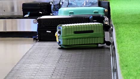 several bags and black suitcases slide on the luggage carousel, baggage claim hall of a modern airport