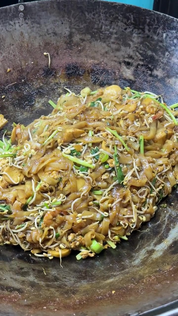 Chef faisant sauter du Char Kway Teow au wok