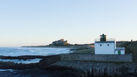 aerial establishing shot of bamburgh castle and coastline during sunset