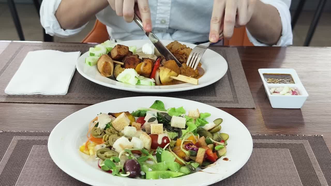 persona comiendo una comida con ensalada y parrilla mixta