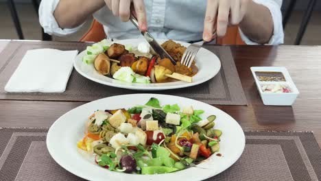 サラダとミックスグリルで食事をしている人