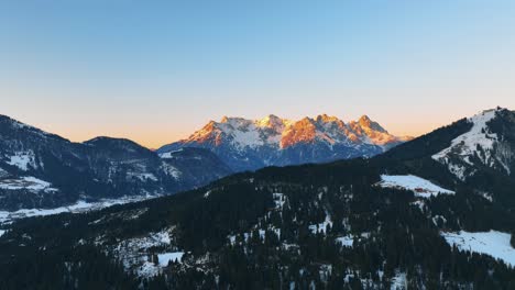 Die-Drohne-Fliegt-über-Einen-Berg-Mit-Bäumen-In-Richtung-Des-Großen-Berges,-Der-Bei-Sonnenuntergang-In-Österreich-Von-Der-Goldenen-Sonne-Beleuchtet-Wird.-Luftaufnahmen-4k