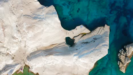 overhead aerial of sarakiniko beach, top down drone close up of white rock coast