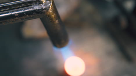 calentamiento de detalles metálicos con llama de quemador de gas para hacer joyas