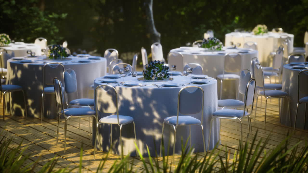 Elegant outdoor dining setup with tables and floral centerpieces at sunset