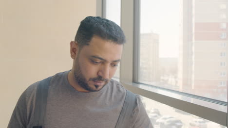 close up view of arabic cleaning man wearing gloves cleaning stair railing inside an office building