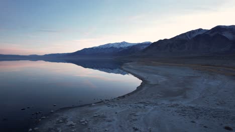 aerial-sunset-seascape-of-Sierra-Nevada-lake-with-mountains-snow-covered-reflection-in-still-water