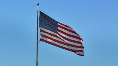 Static-shot-of-an-American-Flag-waving-in-the-wind-against-a-blue-sky