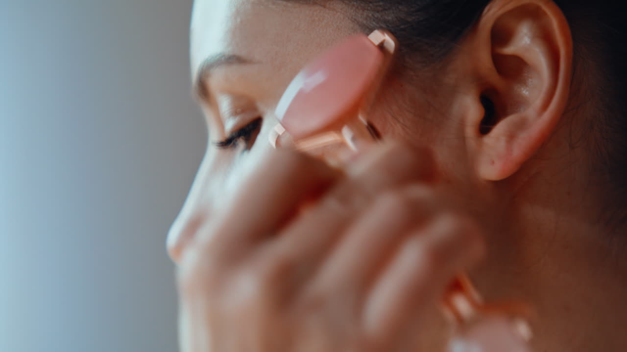 Girl massaging face roller caring of smooth glowing skin closeup. Woman massage