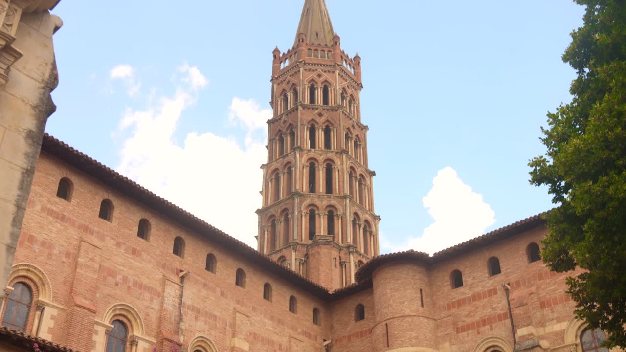 Vista esterna della basilica di Saint-Sernin a Tolosa, in Francia, che mette in risalto l'architettura romanica in pietra con torre e finestre