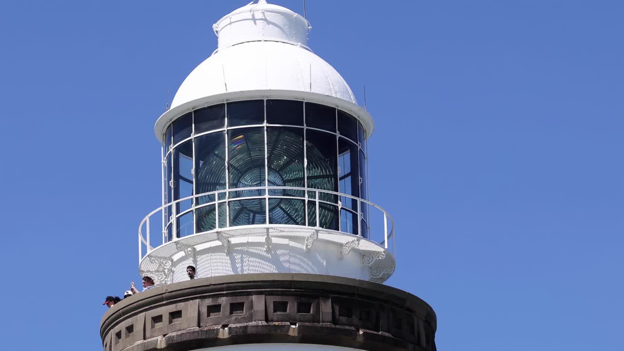 Detailed view of the lighthouse lantern room with a clear blue sky backdrop.