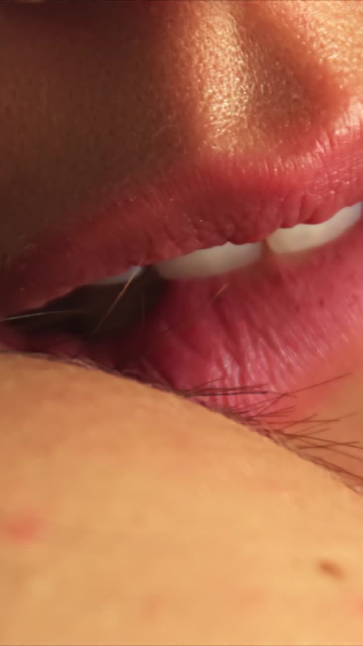 Extreme close-up of woman softly biting her lips in sensual vertical video