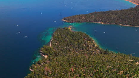 Beautiful blue water of Lake Tahoe, California, USA. Speed boats sailing by the water. Wooded banks from aerial perspective.