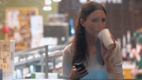 mujer con teléfono inteligente en una cafetería