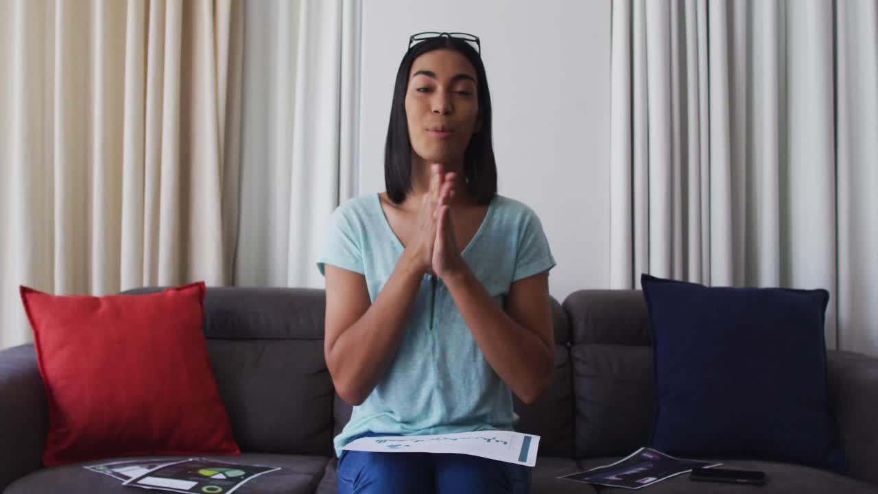 Mixed race gender fluid person sitting on couch having video call at home