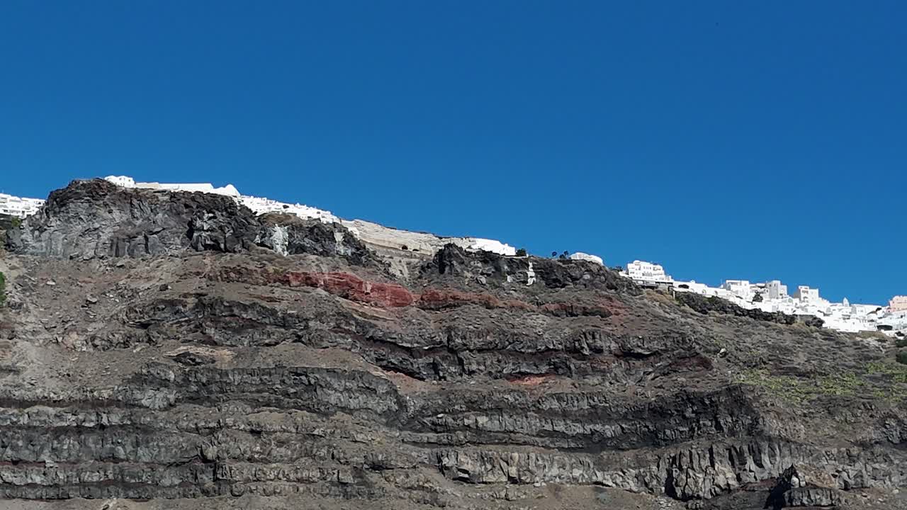 white-washed homes perched dramatically high, lining the volcanic caldera cliffs of Santorini, Greece