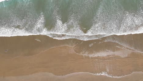 Vista-Desde-El-Cielo-Sobre-Las-Olas-Del-Océano-Y-La-Playa-De-Arena-En-Un-Cálido-Día-De-Verano-Filmado-Desde-Una-Gran-Altura-En-4k