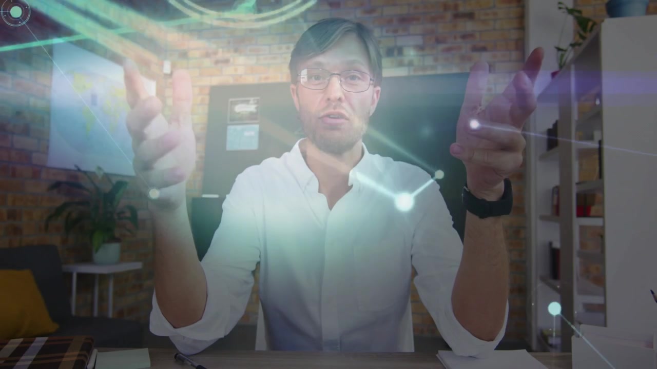 Man at desk starting speaking, gesturing while network overlay passing over hands showing tech