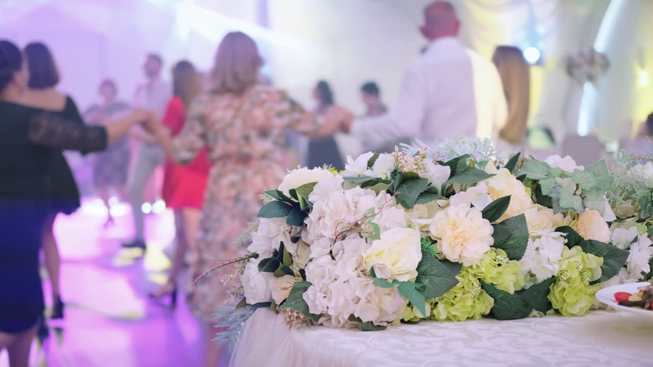 Ospiti che ballano la Hora, una danza nazionale moldava, a un matrimonio. Bouquet in primo piano. Luci del palco