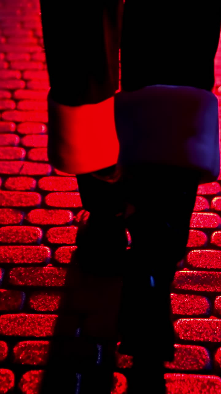 Santa Claus walk on pavement. Legs of Father Frost at Christmas outdoors. Boots of Santa walking on a pavement at dark. Red lighting. Back view. Vertical video