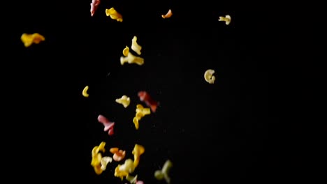 pasta cruda de colores volando sobre fondo negro. camara lenta