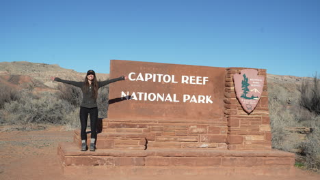 happy young woman by capitol reef national park sign, utah usa