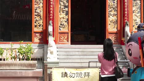 woman approaches temple with cartoon statue