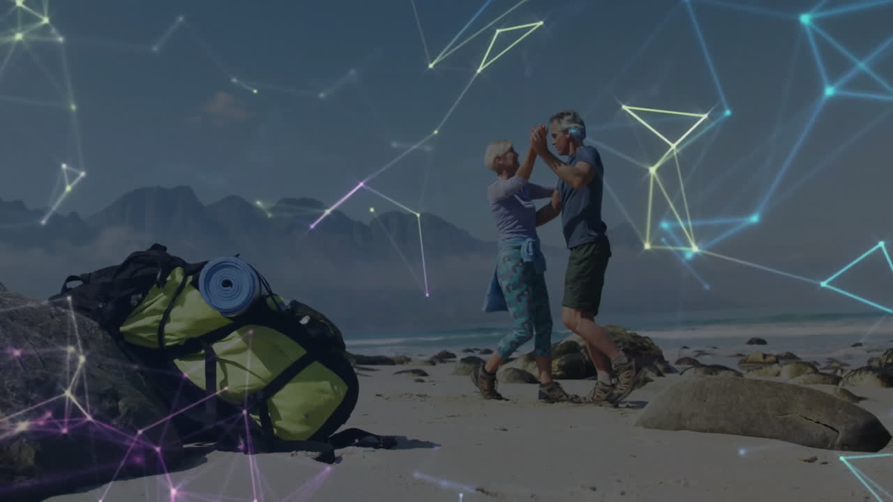 Couple dancing on sandy beach near backpack and mat, showcasing travel technology network
