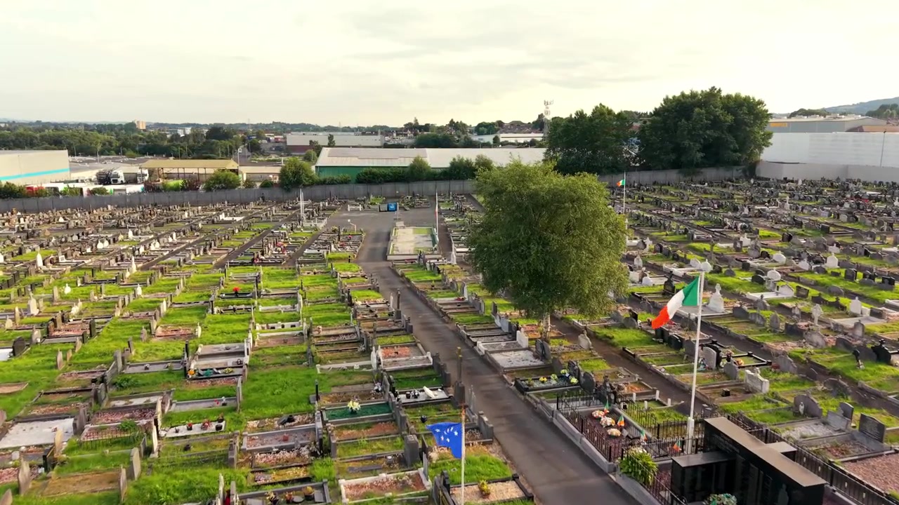 Video aereo 4K a 60FPS con ripresa in avvicinamento del Cimitero di Milltown e del Lotto Repubblicano Irlandese sulla Falls Road a Belfast, Irlanda del Nord, Regno Unito. Prodotto con colore Rec709 pronto per la trasmissione