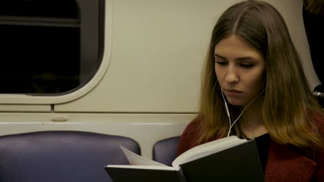 una mujer joven leyendo un libro en un tren.