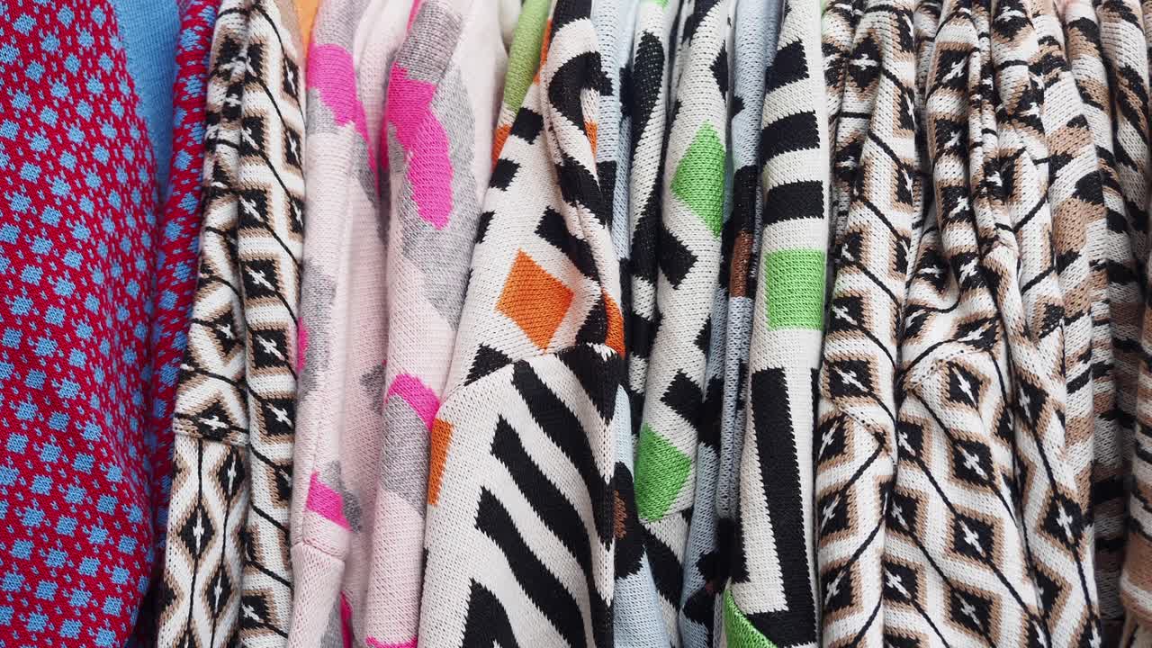 랙 에 있는 다채로운 뜨개질 스웨터