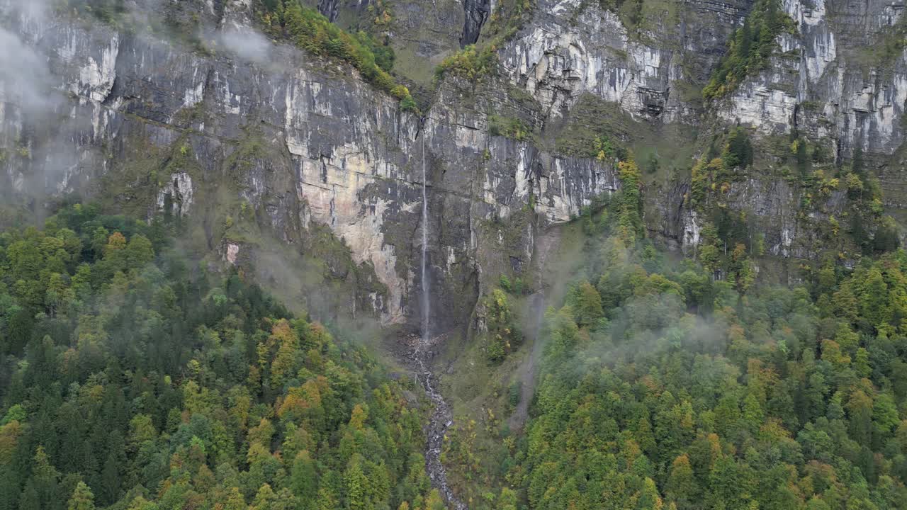 Aerial view of a waterfall with thin stream flowing from a tall mountain summit in Kl&ouml;ntalersee Glarus Switzerland