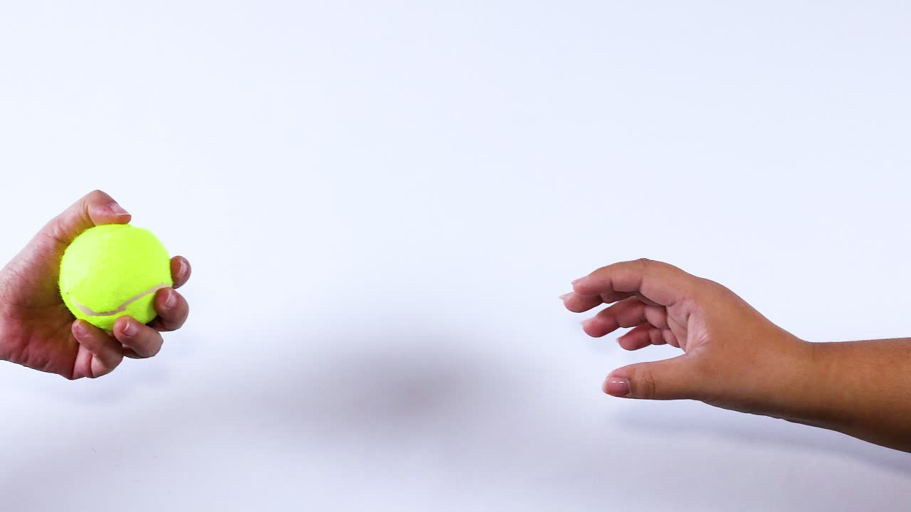 Two hands exchanging a tennis ball