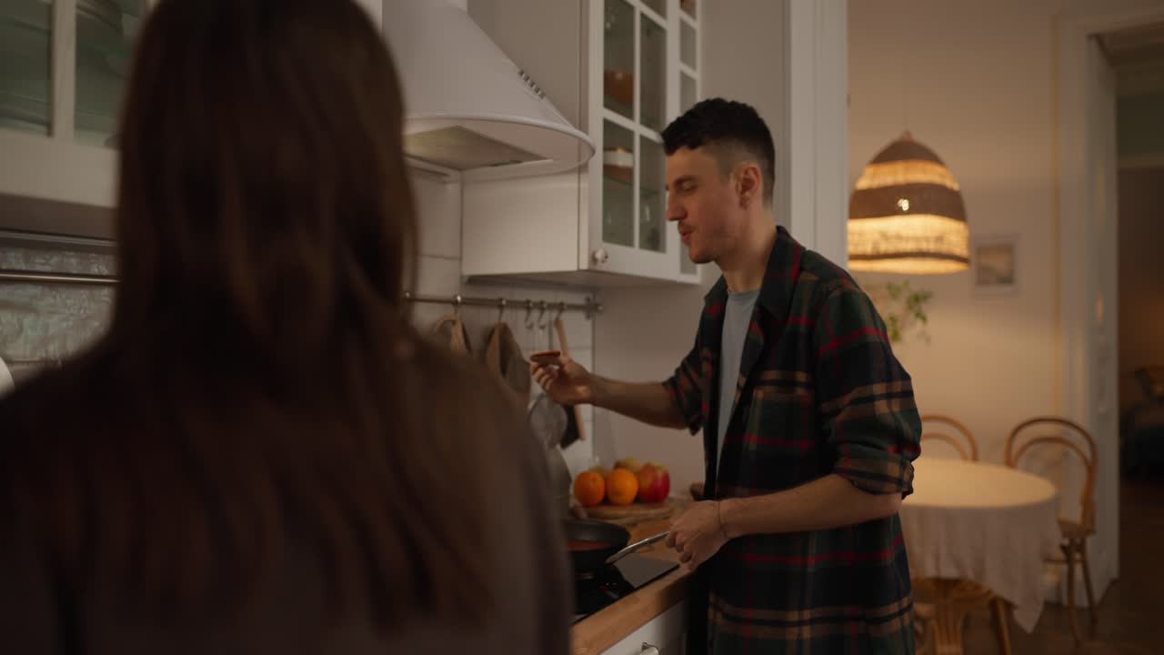 A couple cooking and conversing in the kitchen