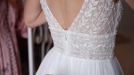 la novia preparándose para la boda, las damas de honor ayudando a cerrar el hermoso vestido blanco, primer plano