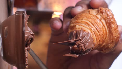 hand holding a croissant with nutella