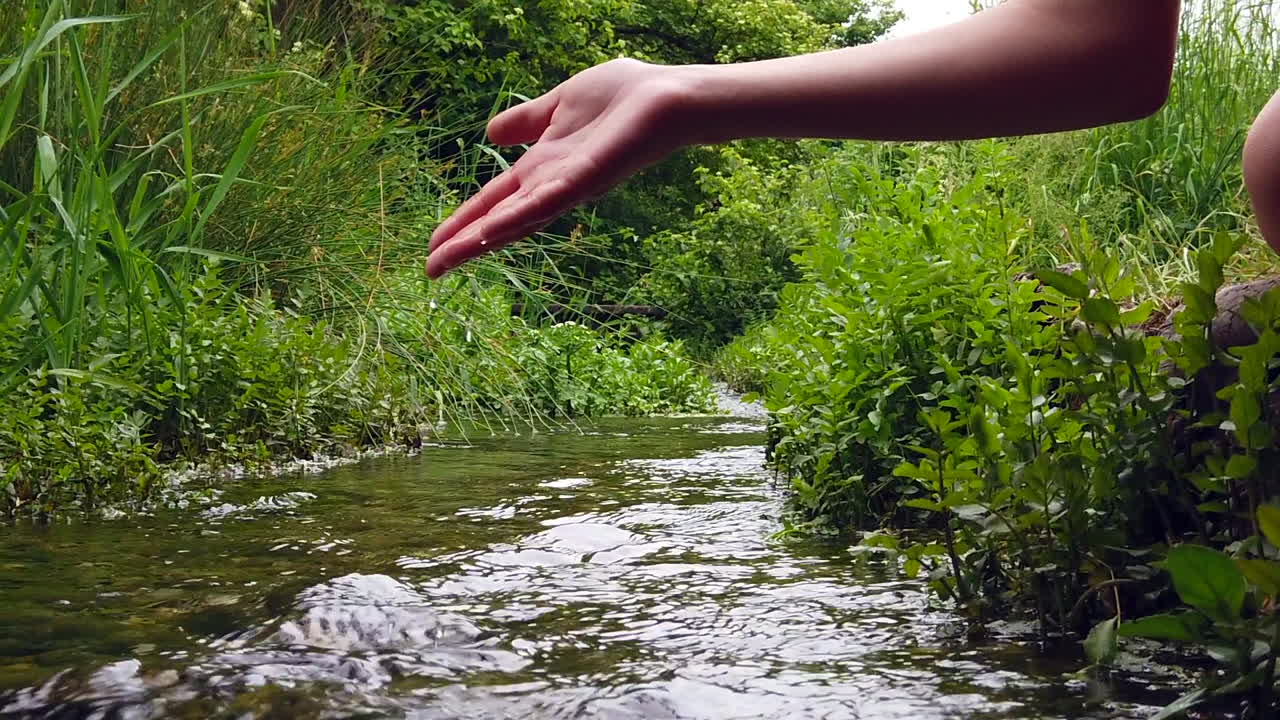 Woman playing with hand in the river.