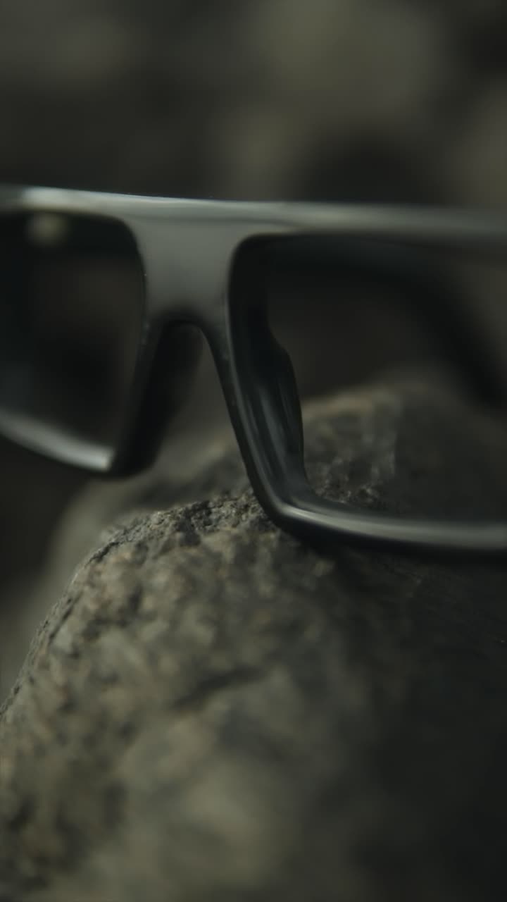 Glasses resting on a rock with a blurred background, focusing on their details