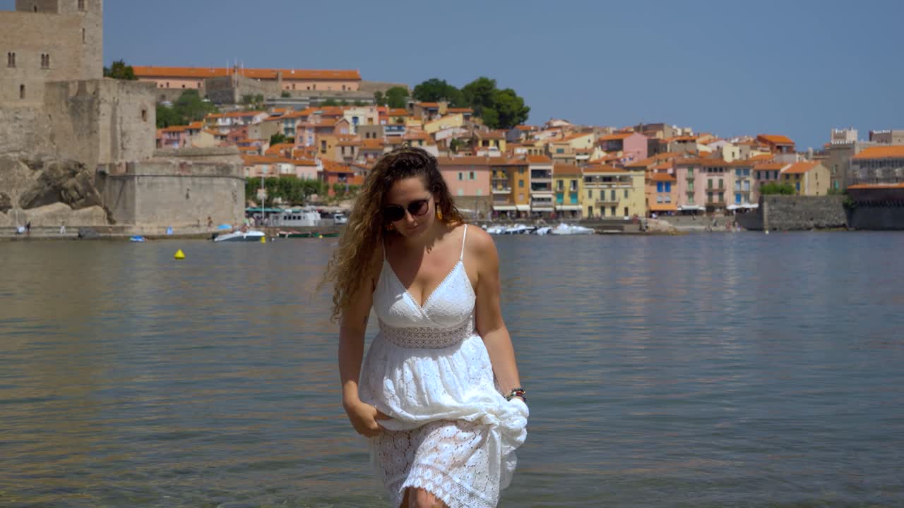 Ragazza carina che cammina lentamente fuori dalla baia di Collioure e gioca con i suoi capelli, Francia