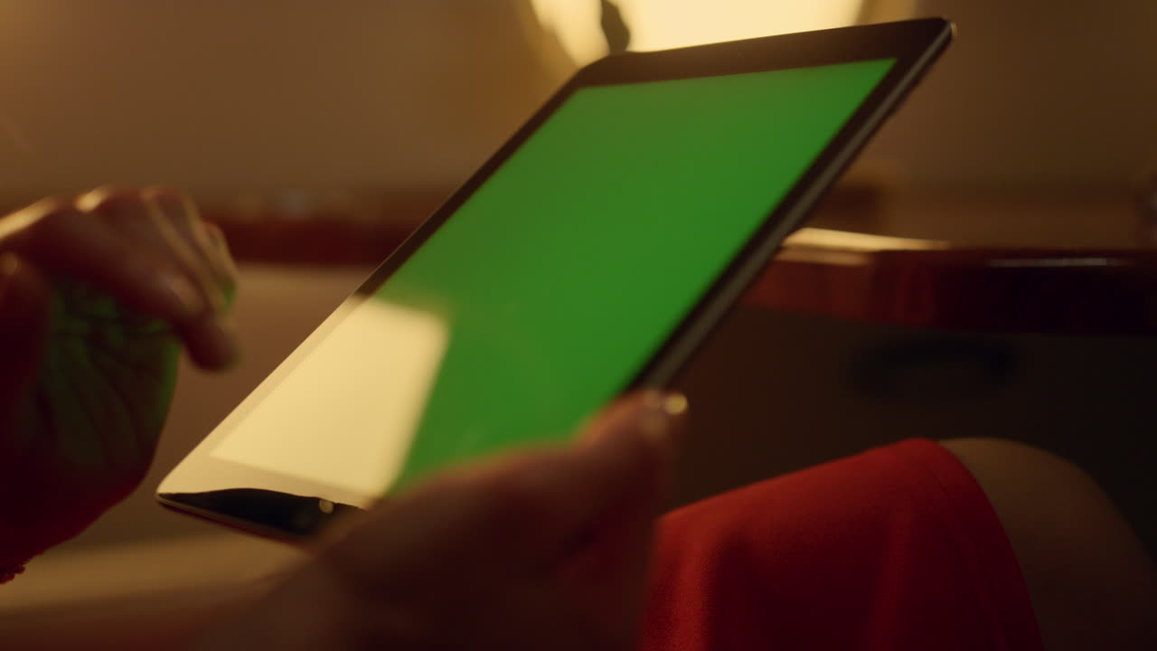 Lady tapping green screen at airplane window. Hands hold chroma key pad closeup
