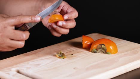 hands slicing persimmon with a knife